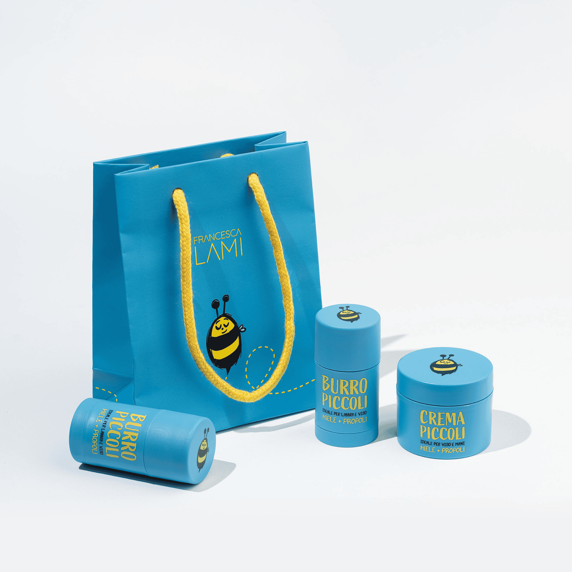 Una confezione regalo azzurra affiancata dai prodotti per bambini Burro Piccoli e Crema Piccoli